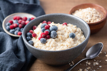 Oatmeal bowl with berries on wooden table, closeup view. Healthy breakfast meal
