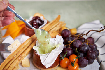Close-up of a cheese plate with mild mold cheese, honey and olives