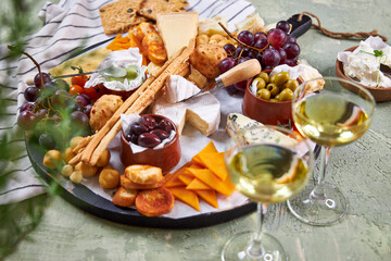 A view from above through the greenery of a large round Charcuterie Board and glasses of white wine...