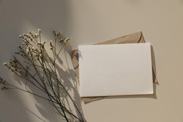 Empty horizontal greeting card, invitation mockup, craft envelope in sunlight, beige table...