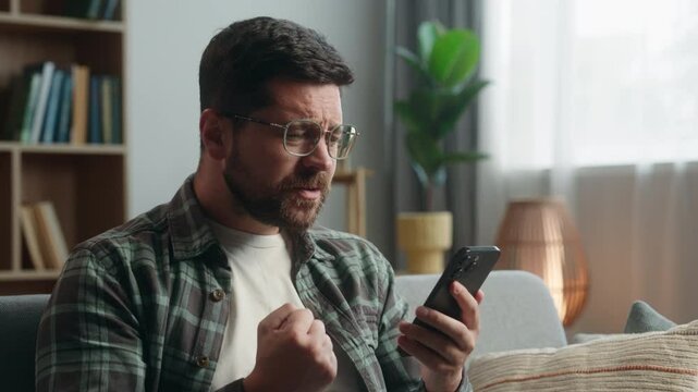 Caucasian man male guy supporter gamer playing video game smartphone at home worried looking at mobile phone online bet gambling sport match betting casino waiting sad disappointed lost failure looser