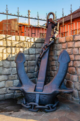 A large anchor stands on the street near a fence. An old Stockless anchor stands near a wall and a fence. Kharkiv city, Ukraine © Vlad Kazhan