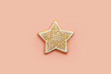 Star-shaped glazed gingerbread cookie on a pink background