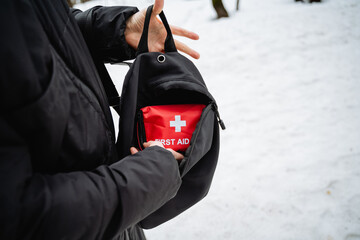 A person is holding a small, portable first aid kit carefully in their hand, ensuring it is ready...