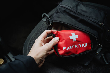 A person is carefully holding a first aid kit in their hand, ensuring it is easily accessible for...