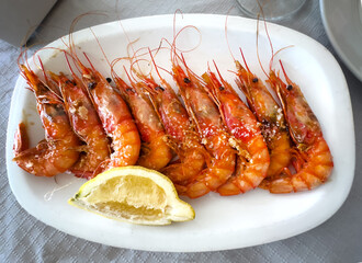 Grilled shrimp platter with rock salt and lemon wedge; top view.