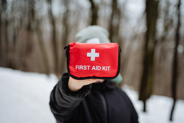A person is holding up a bright red first aid kit right in front of their face, which makes it the...