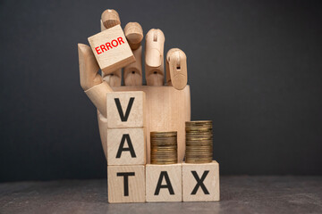 sztuczna dłoń układająca napisy dotyczące finansów: VAT, TAX, 