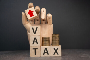 sztuczna dłoń układająca napisy dotyczące finansów: VAT, TAX, 