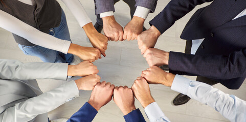 Top-down view of a diverse business group or coworkers team standing in a circle, joining fists...