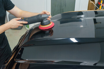 Taking care of the car's appearance. The master polishes the hood of a black car.