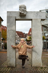 Beautiful Young Woman Posing in Front of a Stone Archway in a European Town with Casual Attire