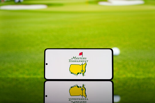 Smartphone displaying Masters Tournament logo with a blurred golf ball and green field in the background. Professional golf championship concept