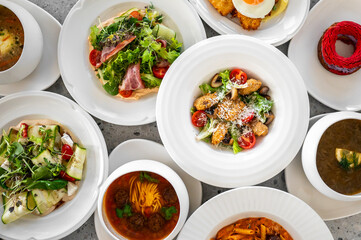 A vibrant assortment of gourmet dishes displayed in white bowls, featuring fresh salads, pasta, and...