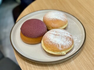 Delicious assortment of three bombolinis with unique fillings—creamy cheese, rich coffee, and sweet purple yam (ubi)—perfect for a tasty snack or dessert. Senayan, Indonesia - February 12, 2025
