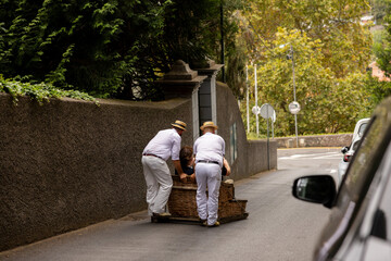 Traditional toboggan men operating a wicker basket car with tourists. Madeira island, Portugal