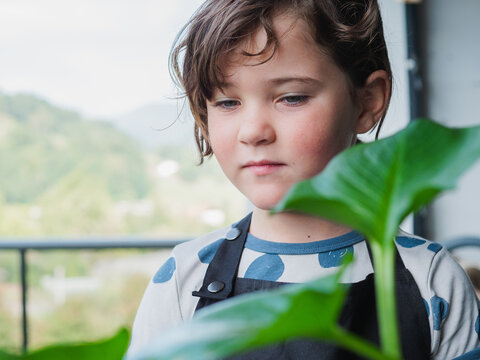 Thoughtful young girl with a green plant indoors