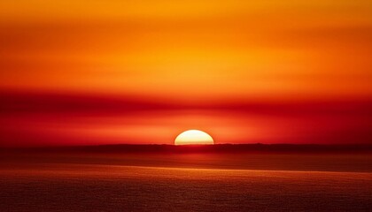 Bright orange and red sunset over dark rolling hills