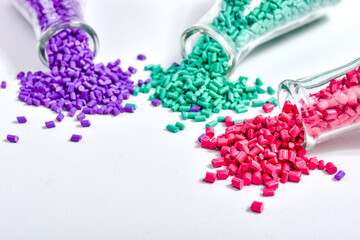 Red, purple and turquoise masterbatch granules in Erlenmeyer flask isolated on white background,...