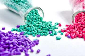 Red, purple and turquoise masterbatch granules in Erlenmeyer flask isolated on white background,...