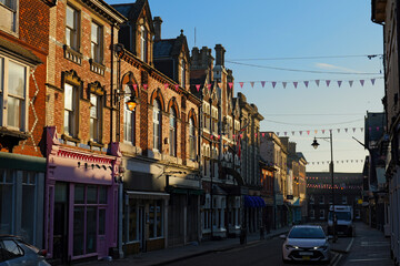 Beautiful historic architecture at golden hour in Swindon, UK. Decorated Wood street in old town. Colorful shop fronts and sun reflection from the windows. Quiet street in the morning.