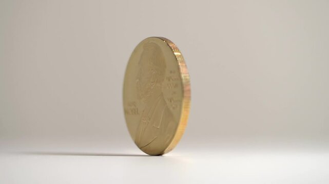 A gold coin with a man's face on it. The man is named Alfred Nobel