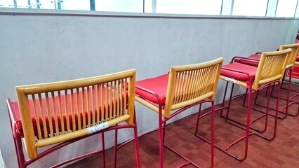 Classic red chair made of woven rattan and foam. Arranged in a room neatly and aligned near the door wall.