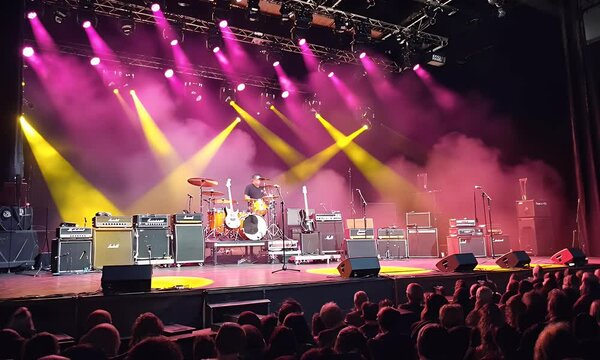 Stage setup for a rock concert with musical instruments, amps, lights, and awaiting audience.