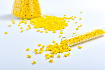 Yellow masterbatch granules in Erlenmeyer flask and glass tube, isolated on white background. Color...