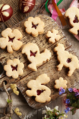 Linzer cookies in the shape of Easter animals and flowers filled with strawberry marmalade, with Easter eggs