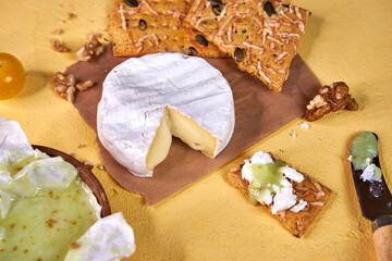 soft white mold cheese with pistachio honey and bread is on the yellow table 
