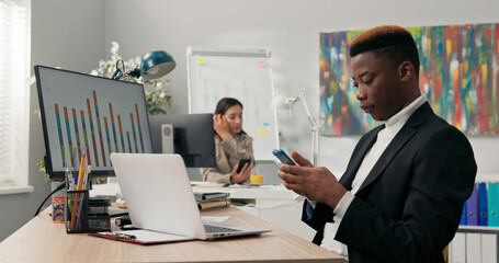 Office workers sit at their desks in front of computer monitors, not attending to their duties, using phones, browsing social media, chatting with friends, a break from work