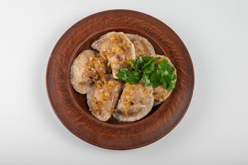 Crispy golden dumplings (varenyky) with sour cream and fresh parsley garnish on a rustic clay plate. Traditional Eastern European cuisine, hearty and delicious	