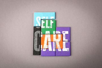Colorful Puzzle Pieces Forming the Phrase SELF CARE on a Grey Background
