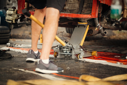 Mechanic Adjusting Racing Car with Hydraulic Jack in Workshop