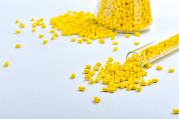 Yellow masterbatch granules in Erlenmeyer flask and glass tube, isolated on white background. Color...
