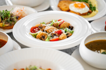 A beautifully arranged plate of fresh salad featuring crispy fried mushrooms, cherry tomatoes, and a sprinkle of cheese, accompanied by various dishes in the background.
