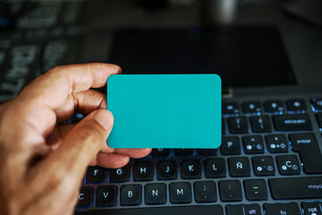 Hand holding blank card over laptop keyboard for online shopping