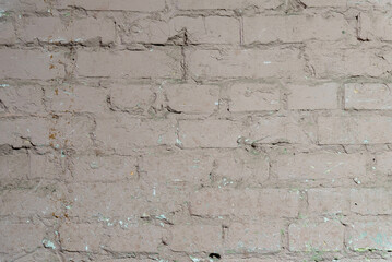 Old brick wall painted in dirty pink with cracks and peeling paint