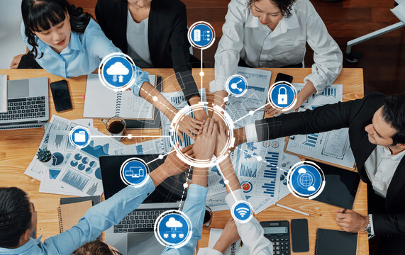 A dynamic team collaborates around a table filled with laptops and charts, fostering innovation and discussing computing trends. Digital icons represent key technology insights. Amity