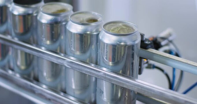 cans in distillery machine being filled and capped