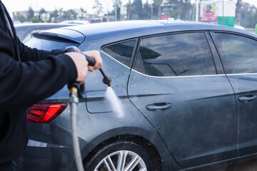 Pressure washing a car at a busy auto detail shop in the afternoon light