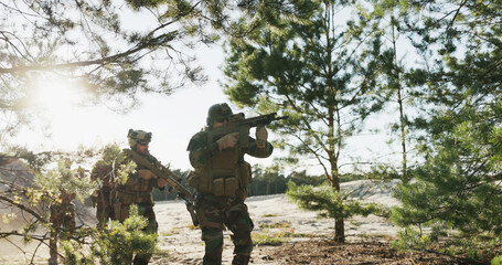 Hidden behind bushes, soldiers in full combat gear march one after another, scanning the area with...