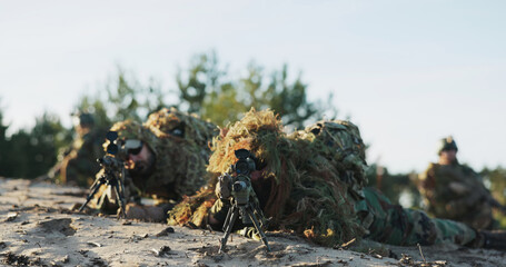 Military men in moro uniforms wear ghillie camouflage made of grass, blending into the environment for stealth operations, prepared for field missions and tactical maneuvers.