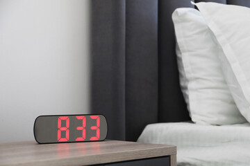 Digital alarm clock showing 8:33 o'clock on bedside table indoors, space for text