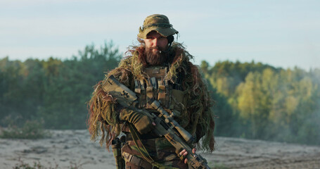 Naklejka premium A strong and focused soldier in full tactical gear, rifle in hand, stands at attention, unholstering his weapon while raising his eyebrows as a gesture of confidence and defiance.