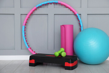 Different fitness equipment near grey wall indoors