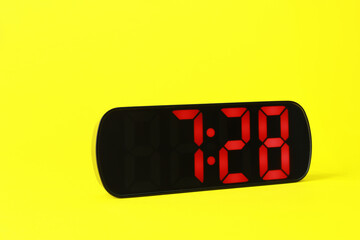 Digital alarm clock showing 7:28 o'clock on yellow background