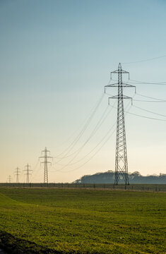 Transmission towers spanning across rural landscape under clear sky