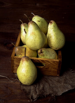 Fresh pears in rustic wooden box with burlap background